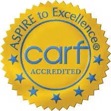 A gold seal with blue text reads ASPIRE to Excellence CARF ACCREDITED and features a circle of blue stars around the border.